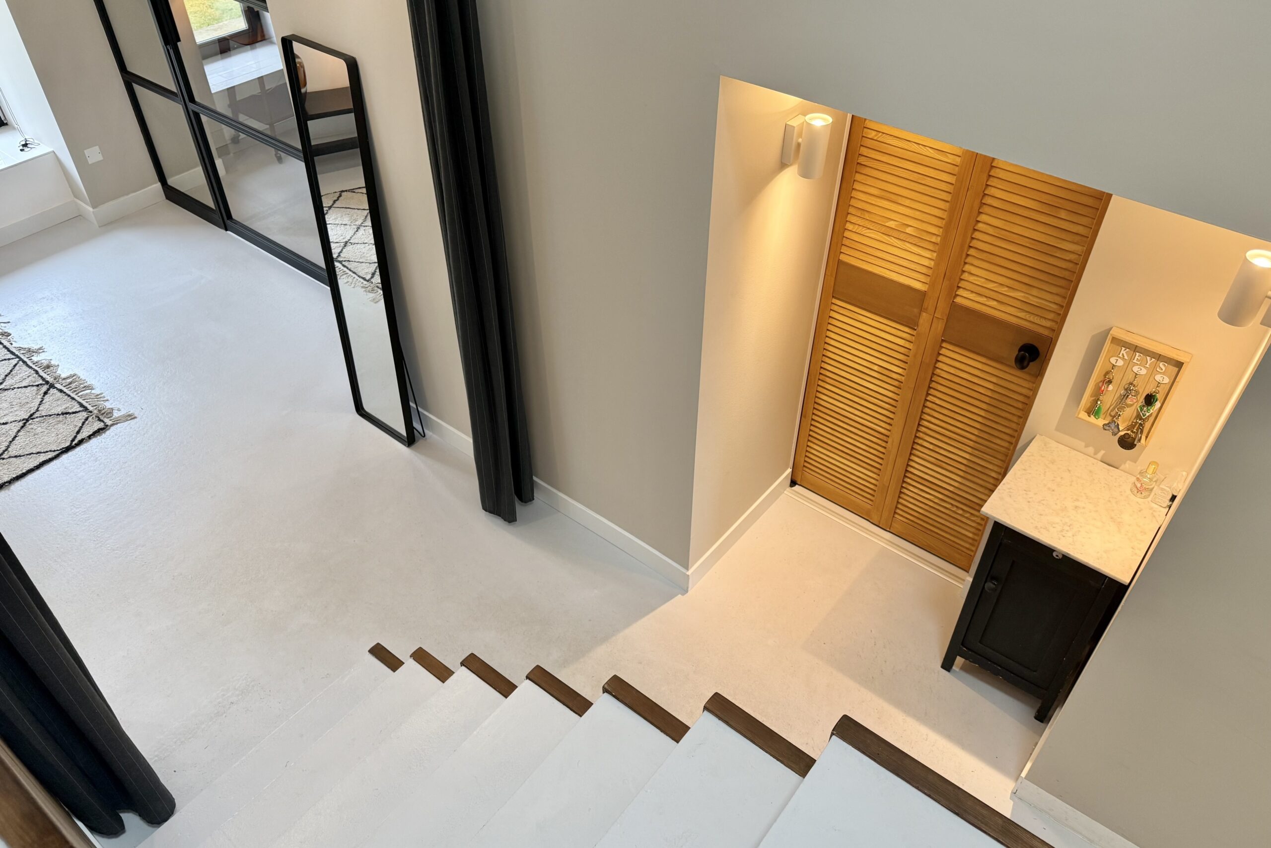 Trappenhuis van beton en houtafwerking in gerenoveerde boerderij met stalen deuren 