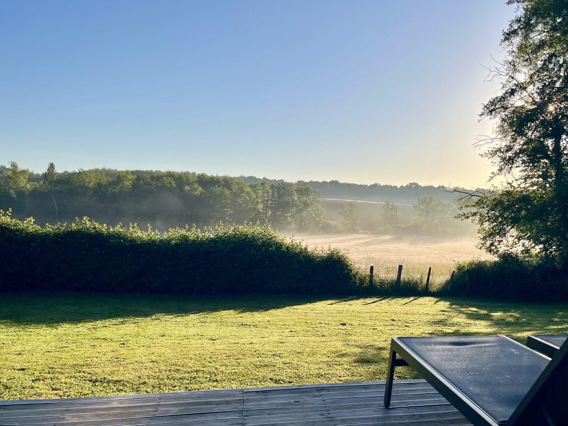 Ochtendmist over landerijen met ligstoel op houten deck bij Le Panorama